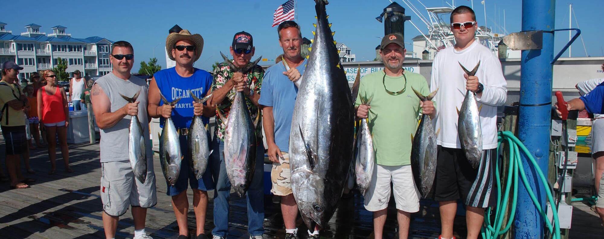 A group of six men holding up their catches for the day